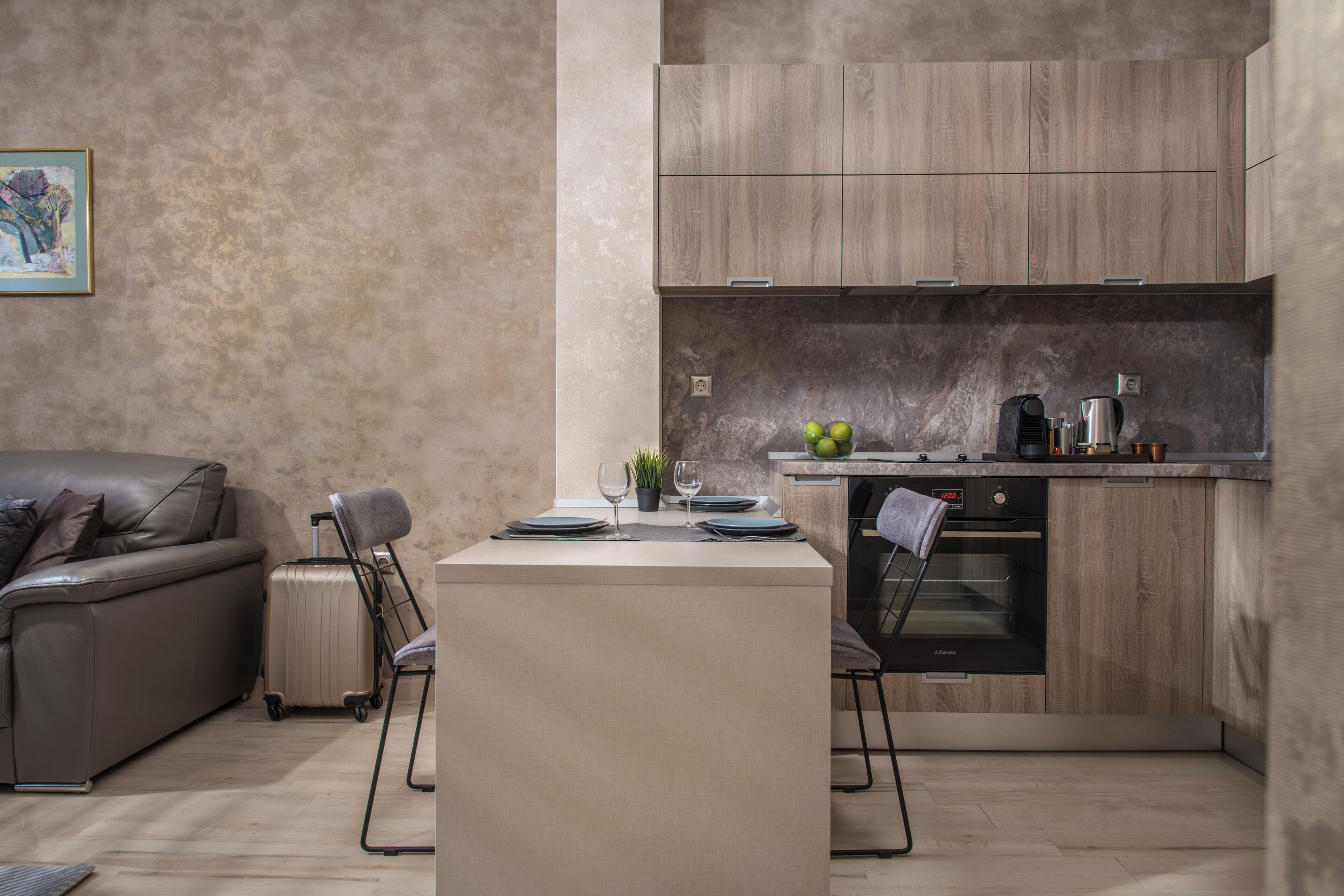 A compact kitchen with wooden cabinets, a built-in oven, and a dining area with a table set for two.