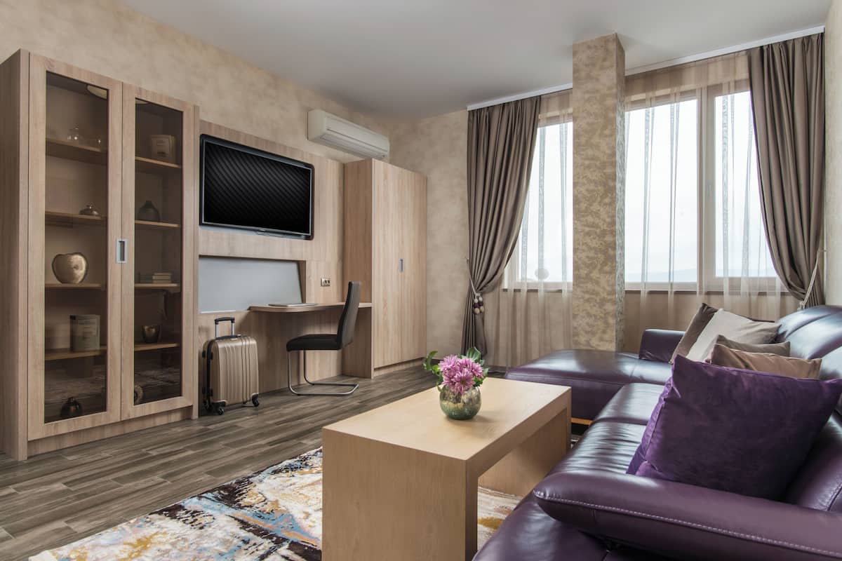 A modern living room with a sofa, a coffee table, a TV, and a desk with a chair.