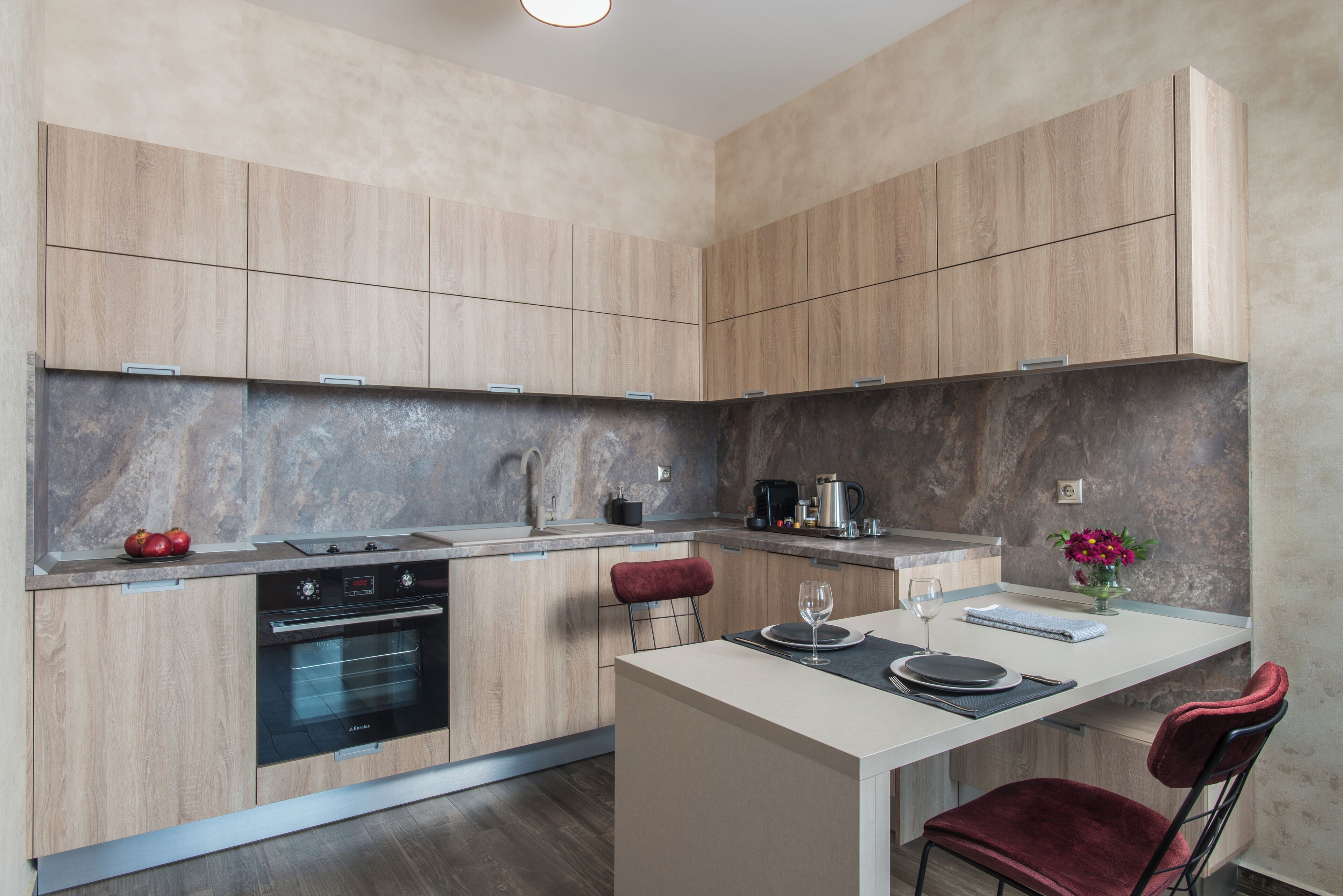 A modern kitchen with wooden cabinets, a built-in oven, and a marble backsplash.