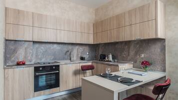 A modern kitchen with wooden cabinets, a built-in oven, and a marble backsplash.