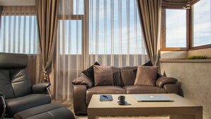 A modern living room with a leather sofa, a recliner, and a wooden coffee table. - Sevtopolis Apartments (Kazanlak)