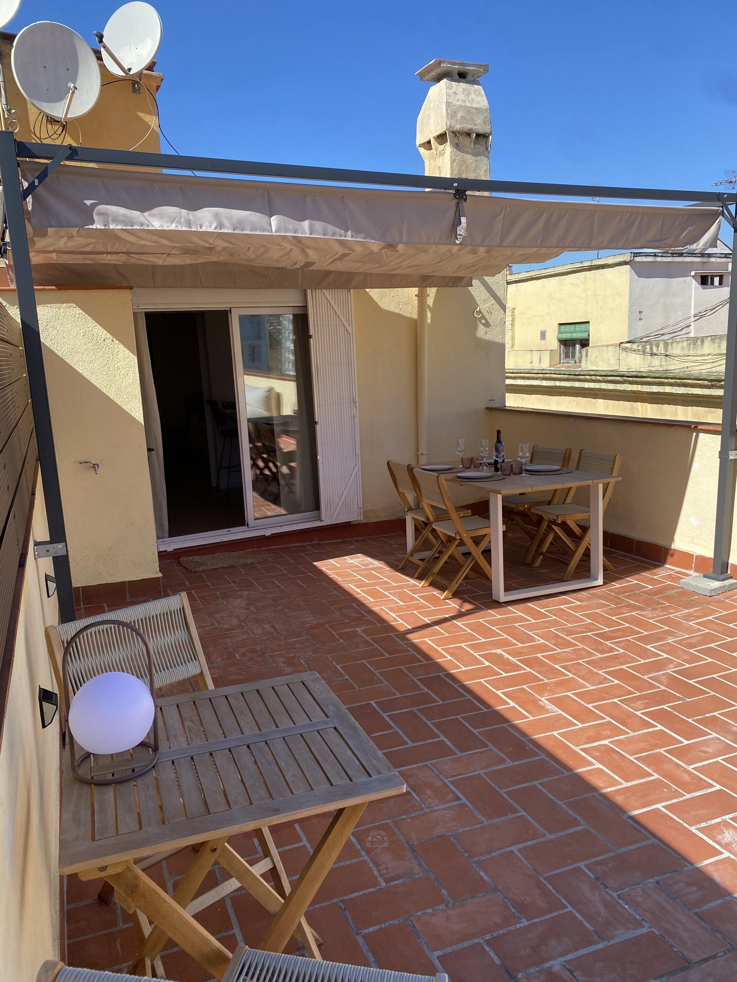 A patio with a table and chairs, a covered seating area, and a sliding glass door leading to an interior space.