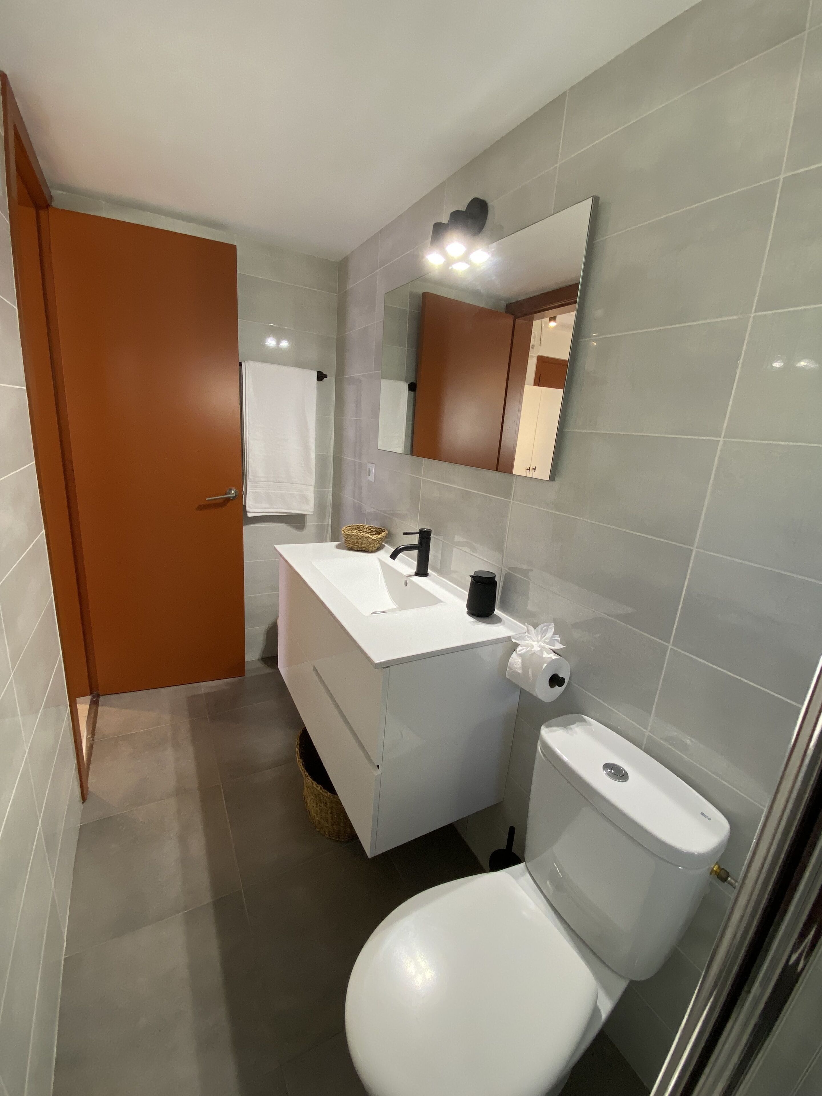 A modern bathroom with a white sink, mirror, and toilet.