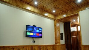 Una habitación con techo y paredes de madera, un televisor montado mostrando la pantalla de inicio, y un armario.