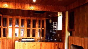 Interior de una cabaña de madera con cocina, armarios de madera y estufa empotrada.
