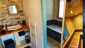 A bathroom with a stone wall, a mirror, a sink, and a shower area.
