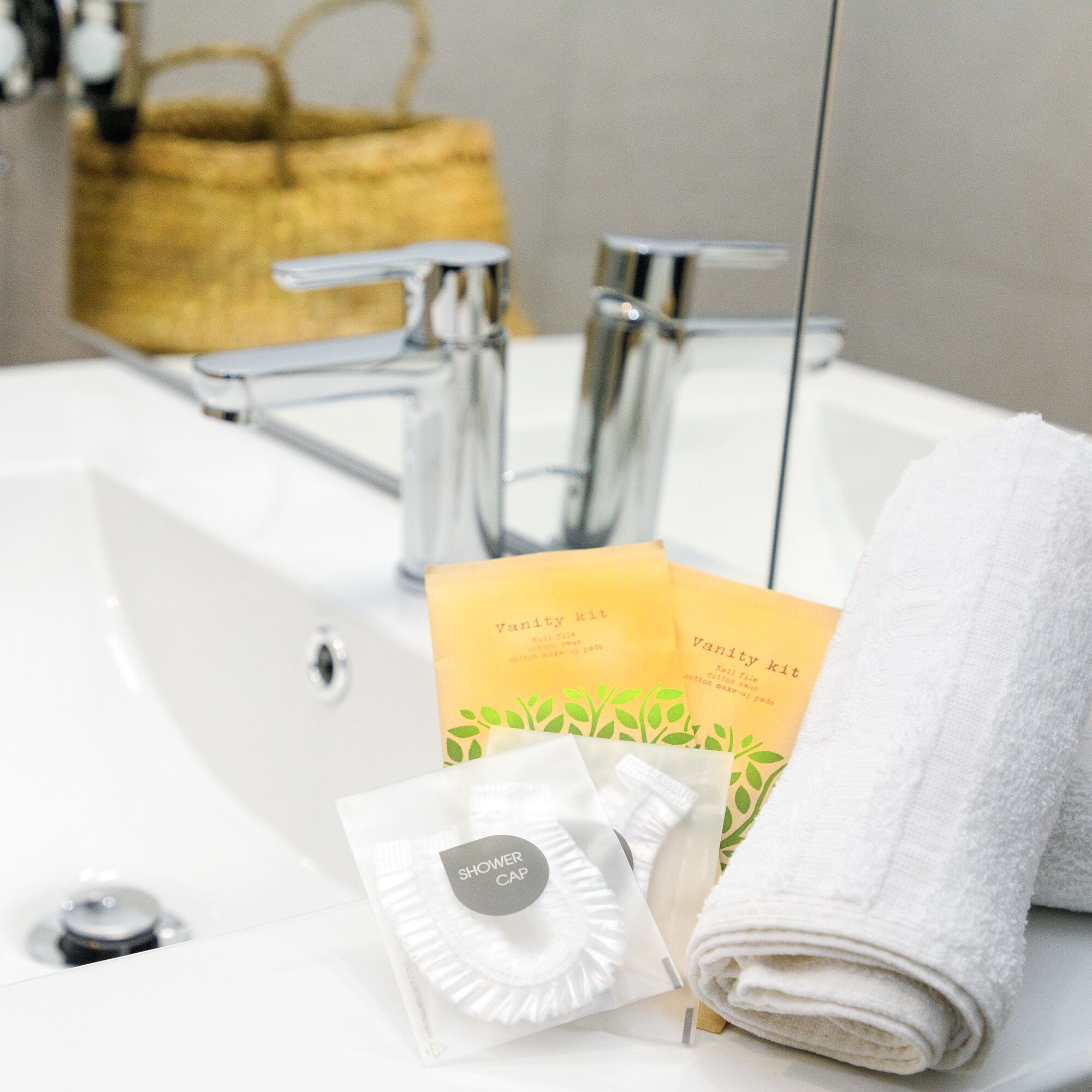 A bathroom sink with a white towel, a shower cap, and vanity kit items.