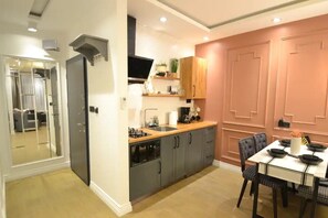 A modern kitchen with grey cabinets, a wooden countertop, and a dining area with a table and chairs.