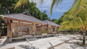 A traditional wooden building with a tiled roof, a covered outdoor seating area, and a sandy courtyard.