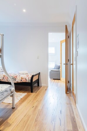 A bedroom with a bed, a bedside table, a chair, and a wooden floor.