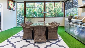 Un comedor con mesa y sillas, una cocina con estufa y vistas a zonas verdes a través de amplios ventanales.