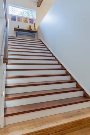 A staircase with wooden steps and white walls, leading to a landing with decorative items.