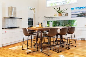 Una cocina moderna con una isla central, taburetes de bar y vistas a zonas verdes por una ventana.