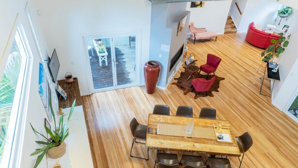 Una habitación amplia con una gran mesa de comedor, varias sillas, un sofá rojo y suelo de madera.