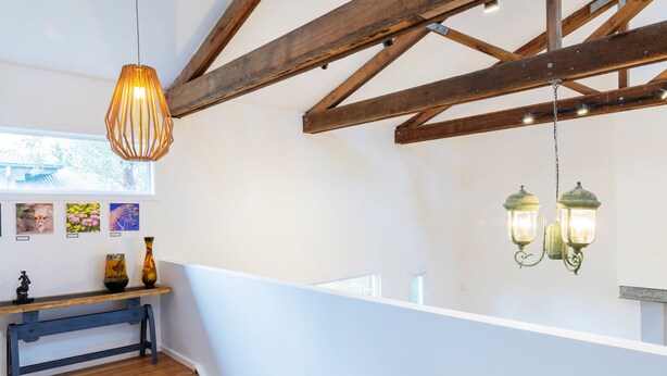 Een trap met houten treden die uitkomt op een plateau met een bank en kunst aan de muur.