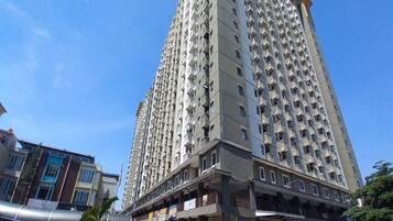 A high-rise residential building with multiple balconies and a ground-level commercial area.