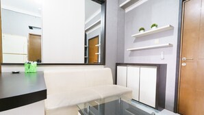 Un salon moderne avec une table basse en verre, un canapé blanc et des étagères intégrées ornées de plantes.