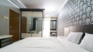 Une chambre d’hôtel avec un grand lit, une armoire, un miroir et un mur décoré d’un motif.