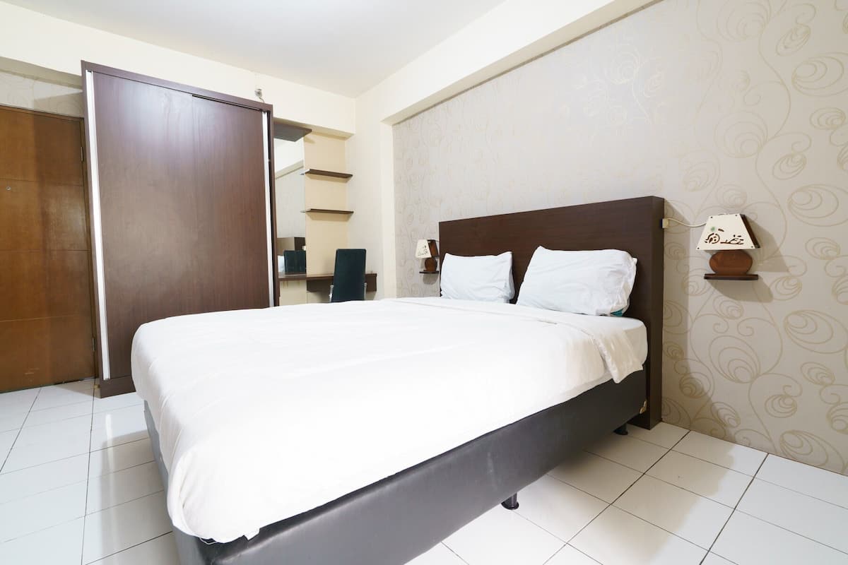 Een hotelkamer met een groot bed, een kledingkast en een nachtkastje met een lamp.