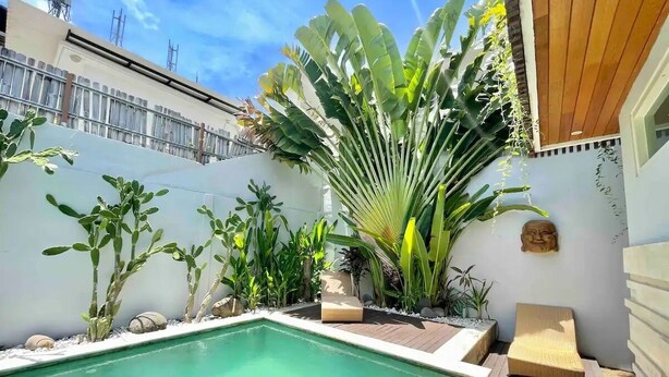 A pool area with a wooden deck, lounge chairs, and various tropical plants. - Mila's Villa Large 3 bedroom villa in the heart Legian. (Bali)