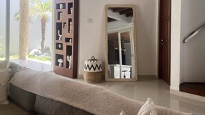 A modern living room with a sofa, a wooden cabinet, a mirror, and a staircase. - Mila's Villa Large 3 bedroom villa in the heart Legian. (Bali)