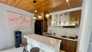 A modern kitchen with a central island, pendant lights, and a refrigerator. - Mila's Villa Large 3 bedroom villa in the heart Legian. (Bali)