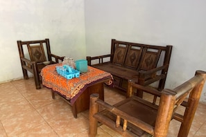 Un banco de madera con un mantel estampado y una mesa pequeña con recipientes de plástico.