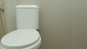 Een wit toilet in een badkamer met een effen betegelde muur.