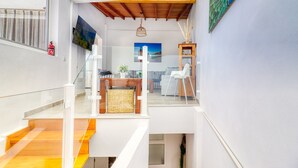 A modern interior with a staircase, a flat-screen TV, a wooden ceiling, and a peacock painting.