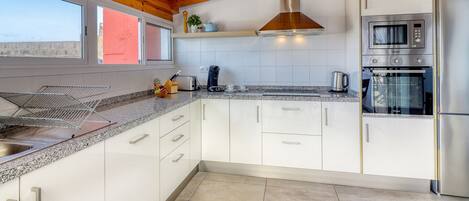 Una cocina moderna con armarios blancos, electrodomésticos de acero inoxidable y techo de madera.