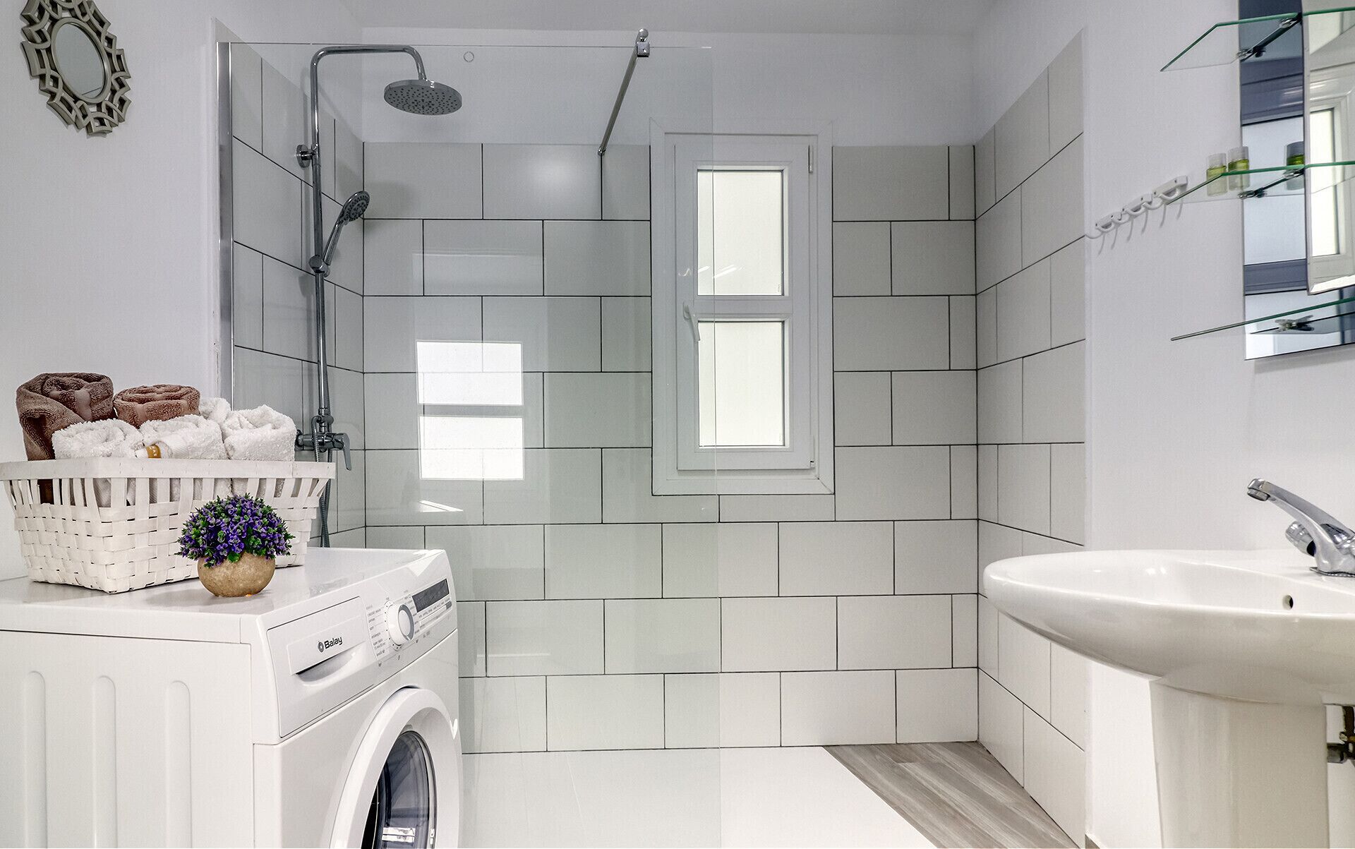 A modern bathroom with a built-in washing machine, a shower, and a sink.
