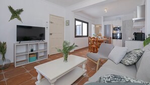 Uma sala de estar com televisão, mesa de jantar e sofá.