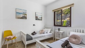 Un dormitorio con dos camas individuales, una mesita de noche pequeña, una silla y obras de arte en las paredes.