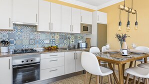 Una cocina con gabinetes blancos, microondas, estufa y una mesa de comedor con sillas.