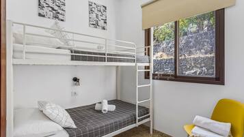 Une chambre avec un lit superposé, une fenêtre, une chaise jaune et deux œuvres d’art murales.