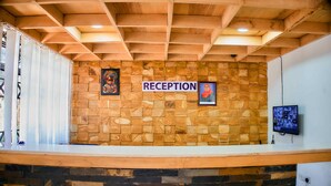 A reception area with a stone wall, wooden ceiling, and a reception desk. - Bluestone Lounge and Lodge. (Arusha)