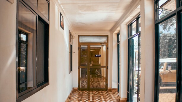 A hallway with checkered flooring, large windows, and a door marked "FULL". - Bluestone Lounge and Lodge. (Arusha)