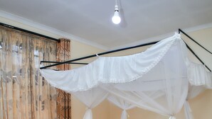 A bed with a canopy, curtains, and a checkered floor. - Bluestone Lounge and Lodge. (Arusha)