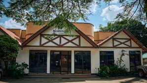 A two-story building with a sign reading "BLUESTO Lodge". - Bluestone Lounge and Lodge. (Arusha)