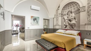 A bedroom with a large bed, a bench, a red headboard, a wall mural, and a hallway leading to another room. - 3737 La Catedral by Barbarhouse (Mesagne)