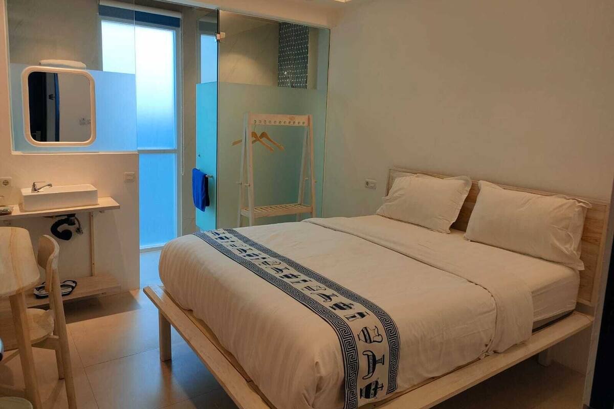 A bedroom with a bed, a bedside table, a mirror, and a wardrobe.