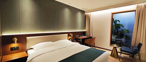 A hotel room with a large bed, a desk, a chair, a TV, and a window with a view.