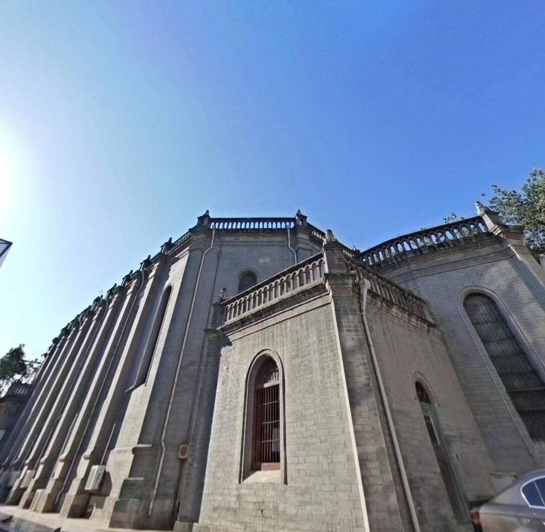 Un edificio grande e histórico con un amplio ventanal de arco y un balcón con barandilla.