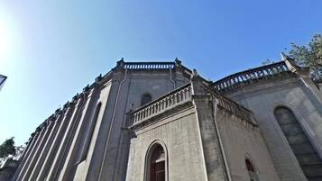 Un edificio grande e histórico con un amplio ventanal de arco y un balcón con barandilla.