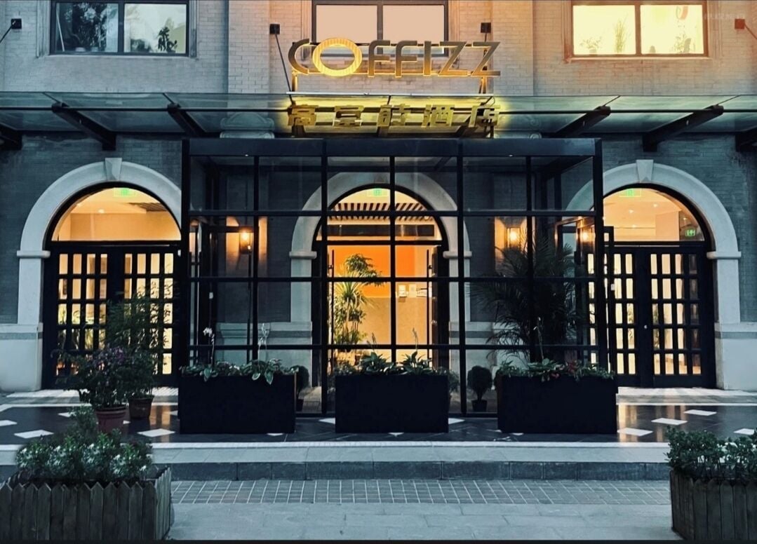 A hotel entrance with a modern facade, large glass doors, and a sign above.