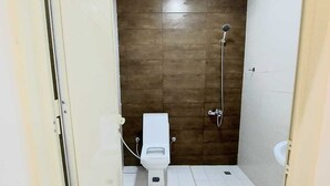 A small, compact bathroom with a toilet, a shower, and a sink. - EK Homes (Ras Al Khaimah)