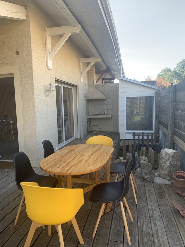 An outdoor patio with a wooden table and chairs, a sliding glass door, and a small shed.