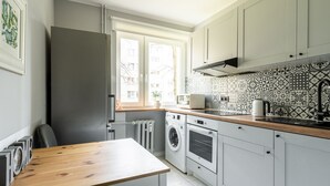 Eine moderne Küche mit Holztisch, integrierten Geräten und einem Fliesenspiegel mit Muster.