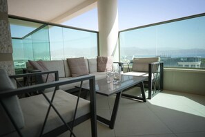 Varanda moderna com divisória de vidro, conjunto de sofás e mesa de jantar.