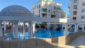 Ein Poolbereich mit Kuppelstruktur, umgeben von einer überdachten Galerie und einem Pool mit klarem, blauem Wasser.